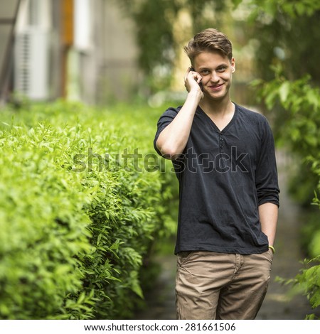 Young guy outdoors talking on a cell phone.