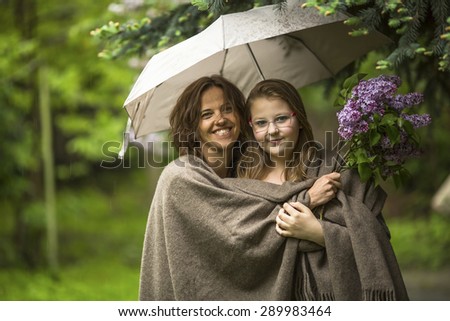 Woman with her daughter standing in the Park under an umbrella.