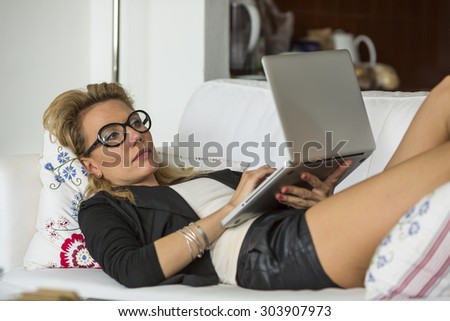 Young woman lying on the couch with laptop.