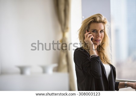 Young business woman talking on cell phone while standing on the balcony of the office.