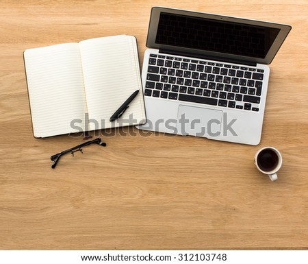 Laptop, open Notepad, pen, glasses and Cup of coffee on the table, light wood. Top view with space for your text.
