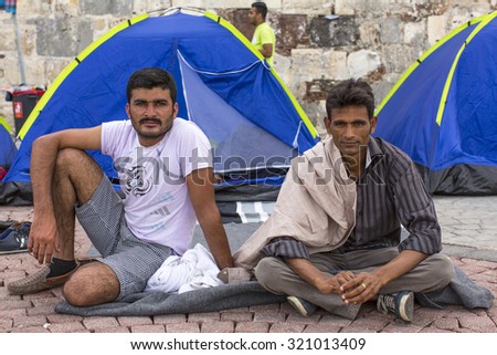 KOS, GREECE - SEP 27, 2015: Unidentified war refugees near tents. More than half are migrants from Syria, but there are refugees from other countries -Afghanistan, Pakistan, Iraq, Iran, Mali, Eritrea.