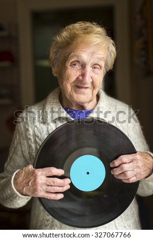 Old woman holding an old LP vinyl record.