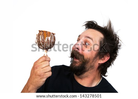 Portrait of a goofy young man, with full beard and moustache and wild hair style, screams with joy at the prospect of eating a candy apple. Studio portrait over white.