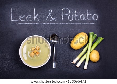 Chalkboard advertising the soup of the day, with a bowl of leek and potato soup and spoon, garnished with bread croutons, with leeks and potatoes on the side