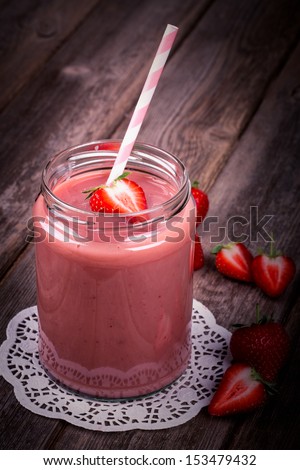 Strawberry smoothie in glass jar, over old wood table. Vintage effect with intentional vignette