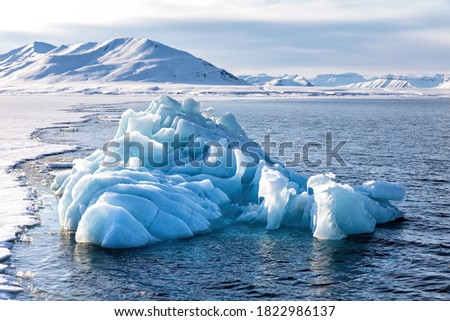 Blue glacial iceberg at the edge of the fast ice, Nordfjorden fjord. Svalbard,.