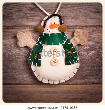 Handicraft Christmas decoration, felt snowman, over old wood background.  Filtered to look like an aged instant photo.