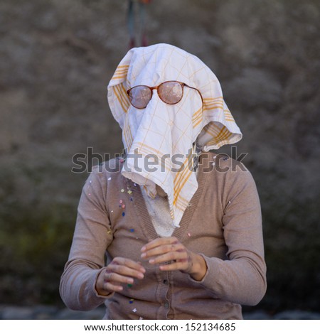 AURILLAC, FRANCE - AUGUST 21:an old woman wears a dish towel on the face as part of the Aurillac International Street Theater Festival, Company L\'arbre aÂ  vache ,on august 21, 2013, in Aurillac,France.