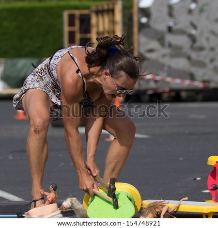 AURILLAC, FRANCE - AUGUST 22: an actress breaks toys with a hammer as part of the Aurillac International Street Theater Festival, Company Monsieur Linea,on august 22, 2013, in Aurillac,France