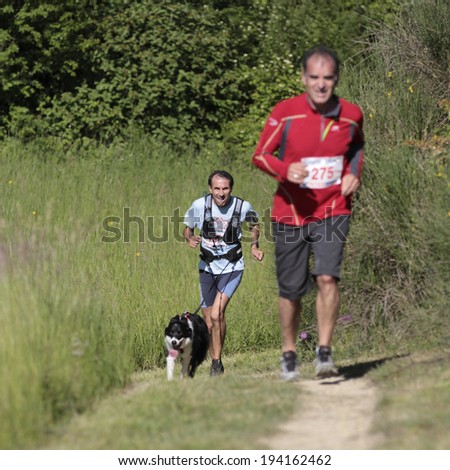 PAVIE, FRANCE - MAY 18: A dog leads a runner who is visually impaired on a countryside path at the Trail of Pavie, on May 18, 2014, in Pavie, France.
