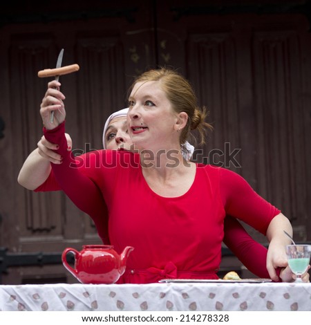 AURILLAC, FRANCE-AUGUST 20: a funny woman looks at a sausage on a fork as part of the  Aurillac International Street Theater Festival, cie Lily Kamikaz,on august 20, 2014, in Aurillac,France.