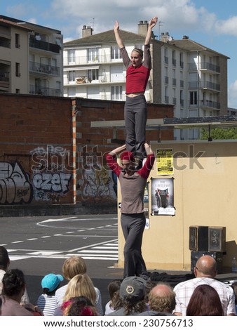 AURILLAC, FRANCE, AUGUST 21: Female acrobat standing on the shoulders of his partner in the street as part of the Aurillac international Street Theater Festival, on august 21, 2014 in Aurillac,France.