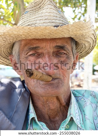 VINALES, CUBA - DECEMBER 16: an old man wearing a straw hat is smoking a cuban cigar outdoors,on december 16, 2014, in Vinales, Cuba