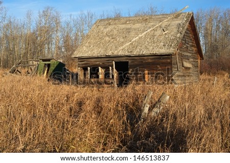 An old abandoned barn in a field of dry grass and weeds,  Image taken in the morning in fall