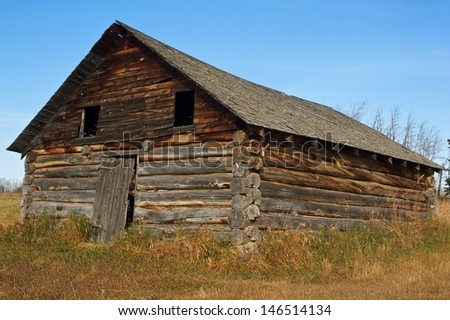old abandoned log barn in fall  Surrounded by dry grass