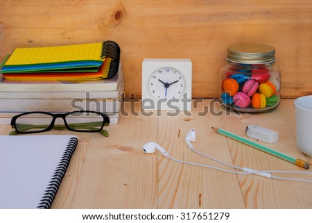 books , glasses, clock ,macaroons and a cup of coffee on workplace desktop