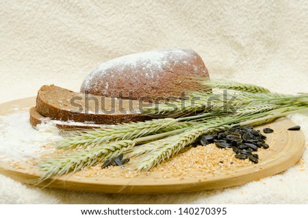 Freshly baked rye bread on a wooden board with ears of wheat, flour, grains and seeds