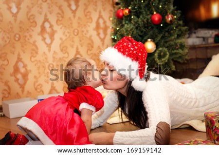 mother kissing her daughter lying on the floor near the fireplace