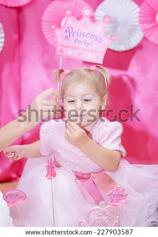 little birthday girl in pink princess dress with a cardboard crown eating cake