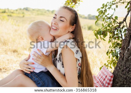 Happy mother and son hugging at a picnic under a tree on a sunny day