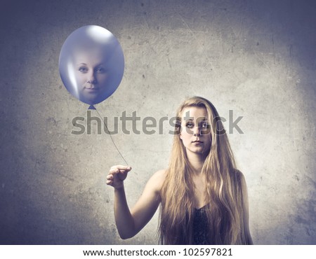 Pretty young woman holding a balloon with her face on it