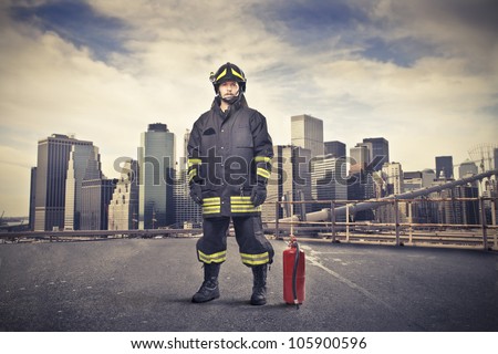 Fireman wearing his uniform with a fire extinguisher beside him and cityscape in the background