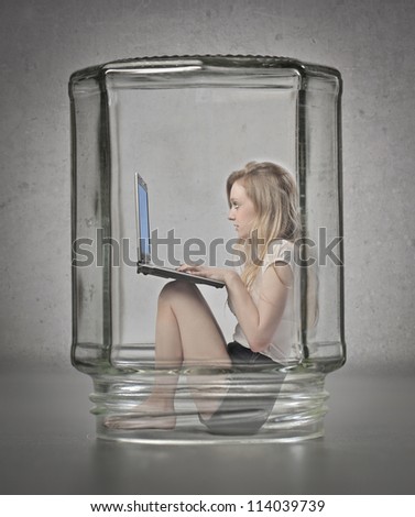Blonde girl using a laptop computer in a glass container