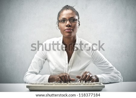 Black woman, with a white shirt, using a computer keyboard