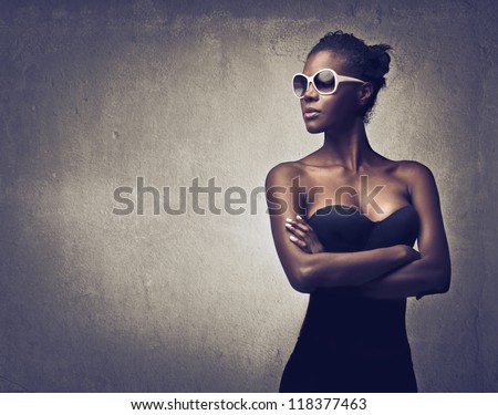 Black girl, with a pair of white sunglasses, posing in black