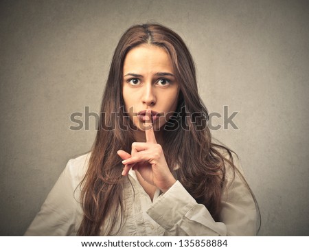 portrait of woman making a sign with her hand to be silent