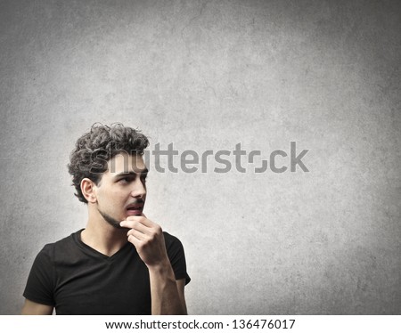 young man thinks on gray background