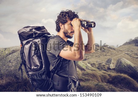 young explorer in high mountain looks horizon with binoculars