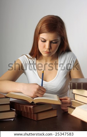 A young pretty student writing on books on the table on a white background