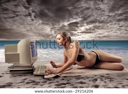 pretty girl in bikini using old computer on the beach