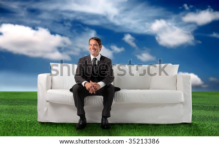 business man sitting on a sofa in a grass field