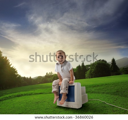 Child sitting on old computer in the countryside
