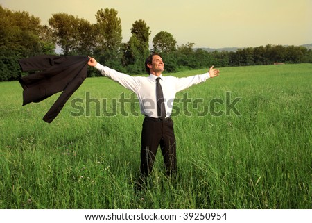 businessman happy and carefree standing  in a grass field