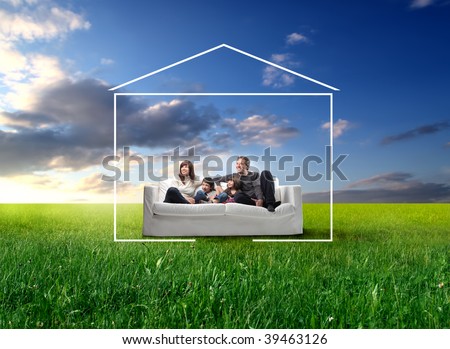 happy family seated on a couch in a grass field and surrounded by home drawing