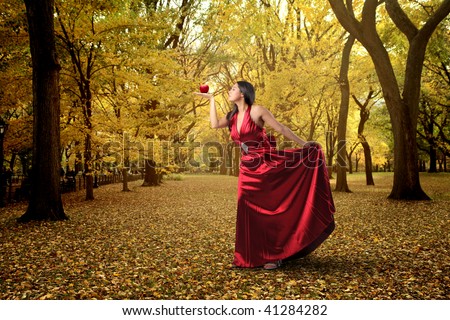 woman in red dress and holding apple in a wood