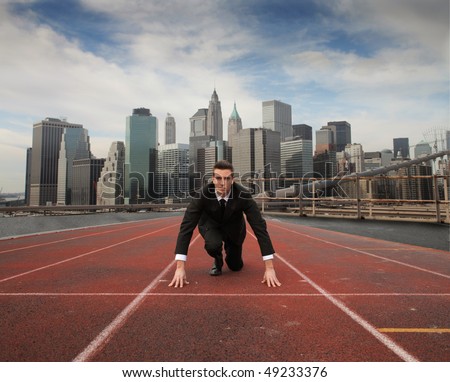 Businessman kneeling on a starting grid with cityscape on the background