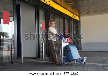 a woman\'s going out from the airport  with a  trolley