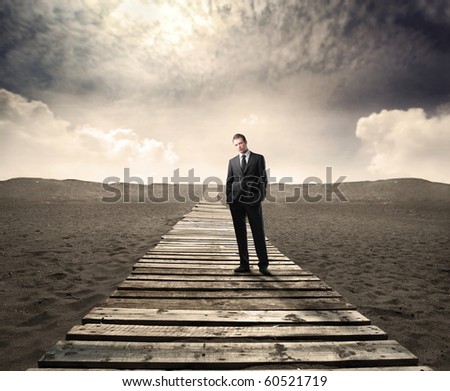 Businessman standing on a wooden path on a desert