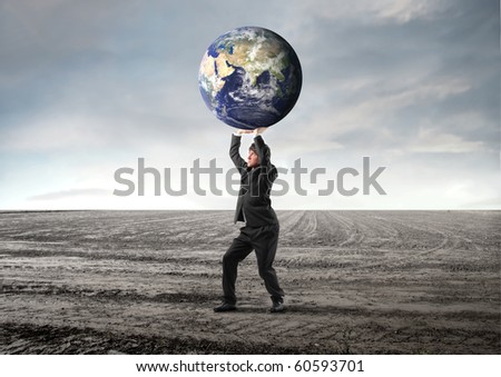 Businessman carrying the earth in his hands on a field
