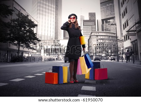 Attractive woman using a mobile phone and carrying some shopping bags on a city street