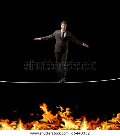 Businessman standing on a rope over a fire