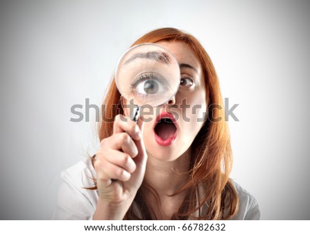 Amazed woman looking through a magnifying glass