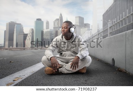 African young man listening to music on a city street