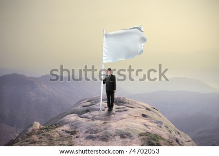 Businessman sinking a flag on the top of a mountain