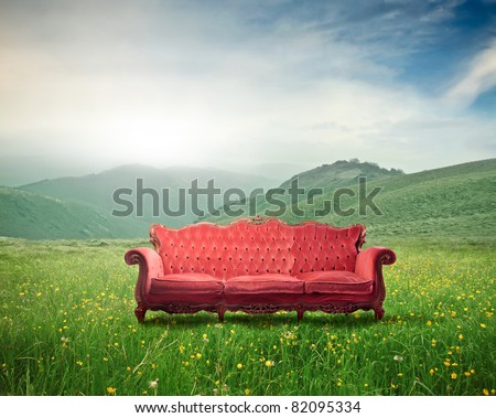 Red velvet sofa on a green meadow